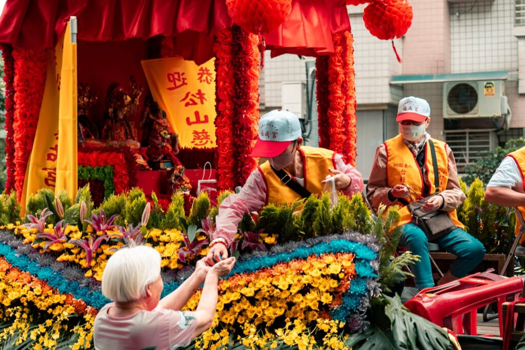 A colorful parade scene with people and floral decorations, showcasing cultural festivities.